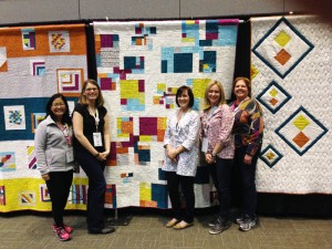 Some of the members of the Southern CT Modern Quilt Guild in front of our guild's charity quilt.