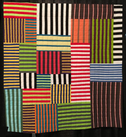 "Striped Chaos" by Maria Shell Statement: "When making the quilts from my book Improv Patchwork—Dynamic Quilts Made with Line and Shape, I wanted to show the design potential present in the simple stripe, also known in the quilting world as a strip set. This quilt is an off-the-grid composition based solely on machine pieced striped fabric.” [Design Source: Traditional strip sets] displayed in the 2018 Modern Quilt Showcase sponsored by the Modern Quilt Guild at the International Quilt Festival in Houston