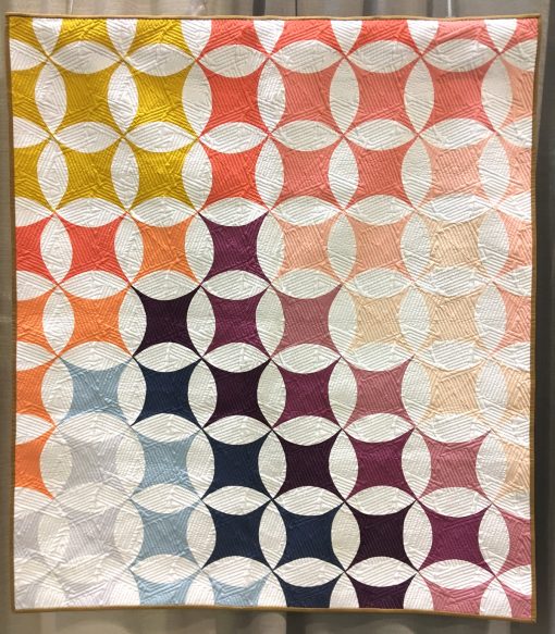 Modern quilt featured at QuiltCon 2019 — “Shades of Citrus” by Brittany Lloyd. Quilted by Jess Ziegler @loandbeholdstitchery Statement: “Shades of Citrus is a fun spin on the negative space of a classic Lafayette orange peel quilt block.”