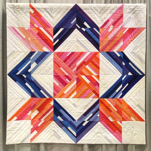 Modern quilt featured at QuiltCon 2019 — “Barn Quilt” by Renee Tallman @uniquilter Statement: “I like barn quilts and I wanted to make a quilt that had the appearance of being painted. When the SBAMQG issued our Make it Modern challenge in 2017, one option was to modernize the traditional weathervane block. I pieced scraps onto muslin foundations in an improv style. I used many shades as I could to convey the idea of a painted quilt block. I added areas where it looked like the paint was peeling of in layers, appearing worn and rough, as if the barn wood might be aging or showing through the paint. Source: traditional block design, called the weathervane block.