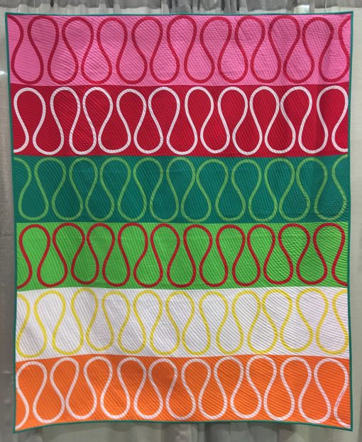 Modern quilt featured at QuiltCon 2019 —“Ribbon Candy” by Emily Parson @emilyquilts Statement: “My family loves ribbon candy! It was a special treat that my grandma had every year at Christmas. Now I buy it for my own kids and they love it as much as I did. I used bias tape applique to recreate the unique shape and festive colors of ribbon candy. Bias tape is easy to manipulate into curves and it comes in lots of great colors. It is a fun process!”