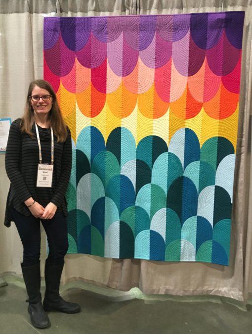 Modern quilt featured at QuiltCon 2019 — "Big Island Sunset" by Sheri Cifaldi-Morrill. Inspiration for Big Island Sunset came from one of my most favorite places in the world—the Big Island of Hawaii. This modern interpretation of the spectacular sunsets on the west coast of Hawaii is entirely pieced from two blocks—a traditional Drunkard’s Path and an elongated Drunkard’s Path.