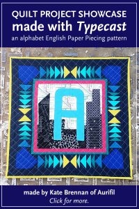 A Alphabet Mini Quilt made by Kate Brennan of Aurifil USA. Chicago skyline made with modern fabric and Typecast English Paper Piecing pattern designed by Whole Circle Studio.