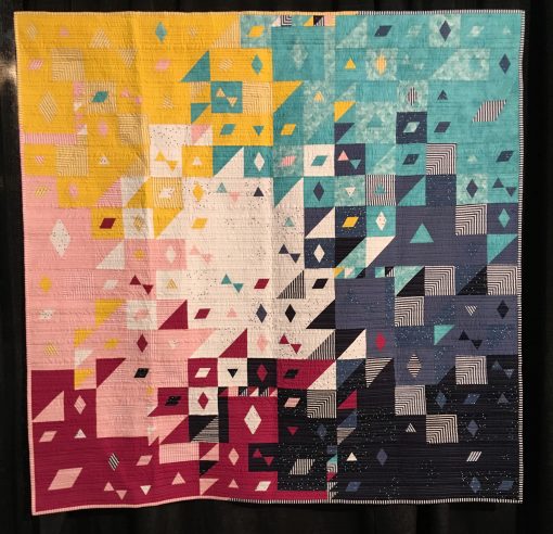 "Blossom Burst" by Sarah Lefebvre Statement: "Blossom Burst is an original quilt design created for the 2019 Riley Blake Designs Modern Quilt Guild Fabric Challenge. I used geometric shapes: triangles, diamonds, and parallelograms paired with organic straight-line quilting to add contrast, texture, and interest.." [Design Source: Original Design | Techniques: Machine pieced and quilted] displayed in the 2019 Modern Quilt Showcase sponsored by the Modern Quilt Guild at the International Quilt Festival in Houston
