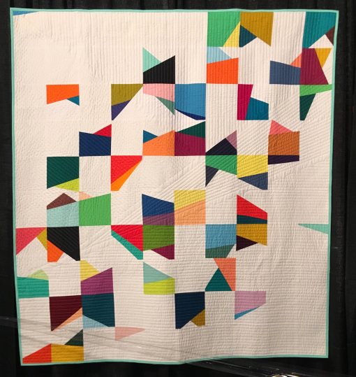 "Correlation" by Michelle Wilkie Statement: "A correlation is a statistical exploration of two factors and how they related to each other. In this study, over 100 days, I was investigating the interaction of color and angles. One block was produced each day, and white blocks were used to balance out the intese colored angles. The straight line quilting of the quilt mimics angles from a single block." [Design Source: Original Design | Techniques: Machine pieced and quilted] displayed in the 2019 Modern Quilt Showcase sponsored by the Modern Quilt Guild at the International Quilt Festival in Houston