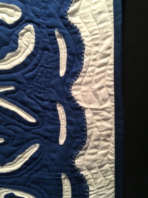 detail of Blue Hawaii by Unknown Maker. Quilted by Ellen Phillips. The quilt top was donated to the Texas Quilt Museum in 2015 by Karen K. Buckley. The top was quilted by local Houston longarm quilter Ellen Happe Phillips in 2018. Echo qulting was selected to complete the quilt in the traditional Hawaiian method. The unknown hand appliquer was an expert in her craft. On loan from the Texas Quilt Museum. Techniques: Hand appliqued, machine quilted. Design Source: Hawaiian quilting. Photo taken at 2019 International Quilt Festival