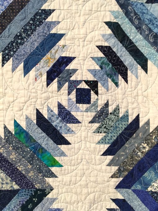 detail of Emily's Pineapple Log Cabin by Sherrilyn O. Phelps. This began as a learning experience for me as a new quilter. It was for my daughter, so she picked the blue and white colors. I learned the block and then added my own borders after I got a longarm quilting machine. It was an exercise in learning. Techniques: Machine pieced. Design Source: Pineapple Log Cabin. Photo taken at 2019 International Quilt Festival