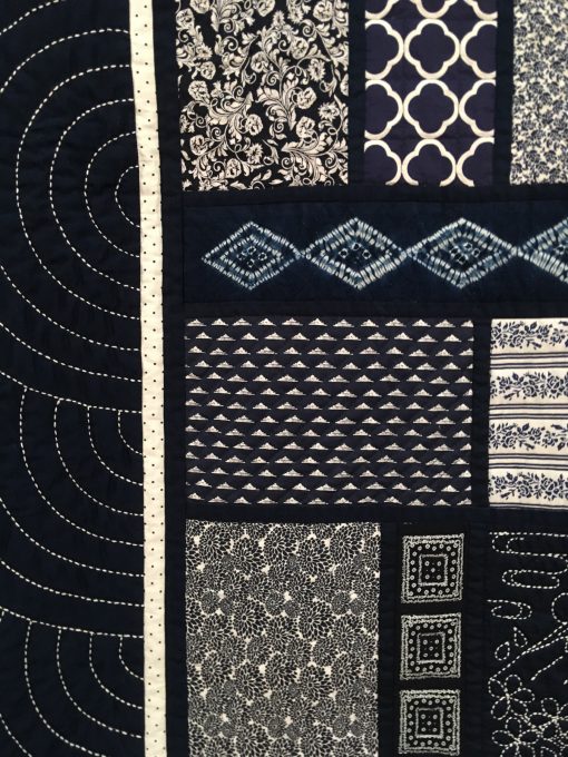 detail of Japanese Memories by Kathleen M. Littfin. I made 16 large blocks, each containing a sashiko piece and one or two shibori pieces, and several other blue and white fabrics in various sizes and styles to complement each other. I'm please that in the finished quilt, it's difficult to discern the blocks. I enjoyed the sashiko so much that I also designed it into the border. There is something so esthetically pleasing about the blue and white quilts, and this quilt contains only those two colors, but many combinations, textures, and patterns.. | Techniques: Hand embroidered, machine pieced and quilted | Design Source: Shibori fabric | Photo taken at 2019 International Quilt Festival