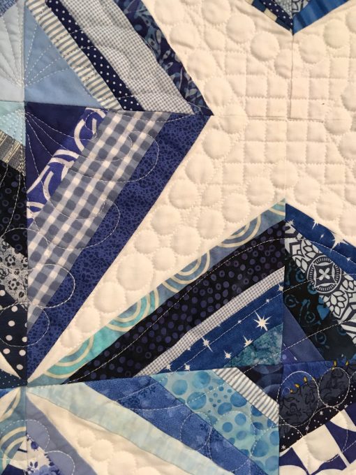 detail of Ice Crystals by Cheryl Degan. Quilted by Emily Bowers. This was my first ever string pieced quilt. I love this quilt because it reminds me of the fun I had sewing with my dear friends on a weekend quilting retreat. | Techniques: Machine pieced and quilted. | Design Source: Images on Pinterest | Photo taken at 2019 International Quilt Festival