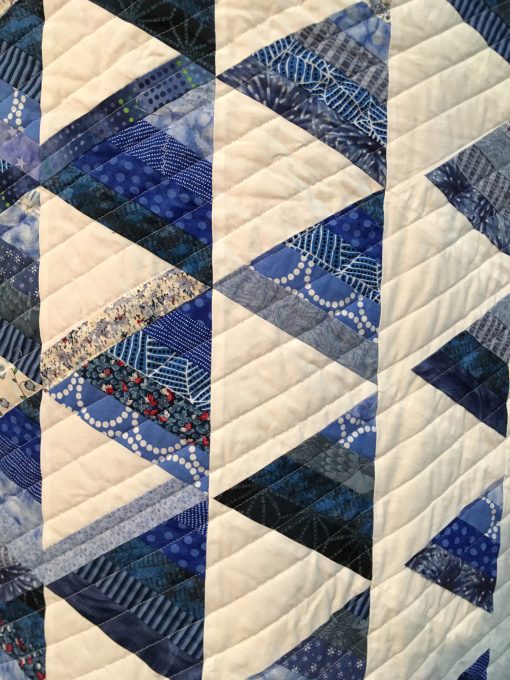 detail of Trifecta by Joy F. Palmer. I saw a similar quilt by Tanya Finken in Fons and Porter's Love of Quilting. I thought I could make a quick simple quilt, but more than three months later, I was still working on it with lots of undoing and mixed up rows. Finally, I quilted it with a longarm machine with the quilt tilted in the machine—also an interesting learning experience. | Techniques: Machine pieced | Design Source: Tanya Finken's quilt in Fons and Porter's Love of Quilting | Photo taken at 2019 International Quilt Festival