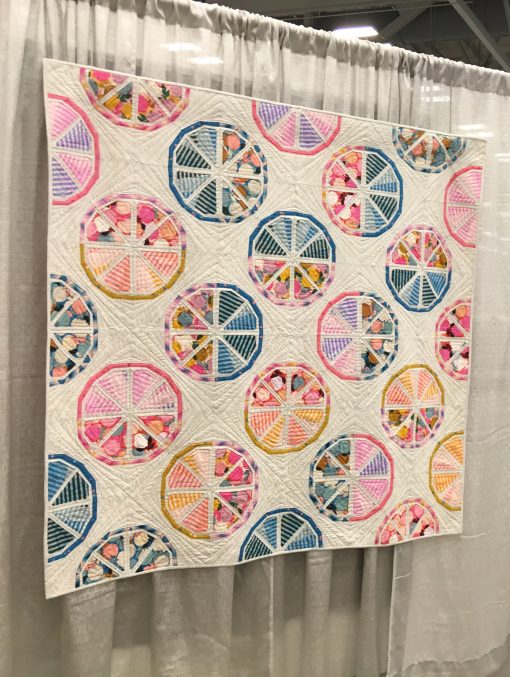 "Citrus Slices" by Sheri Cifaldi-Morrill @wholecirclestudio Statement: “Citrus Slices is an exploration in balancing bold prints and graphic pieced shapes with strong graphics created by quilting in the negative space.” Modern quilt featured in the Piecing category at QuiltCon 2020 in Austin, Texas presented by the Modern Quilt Guild.