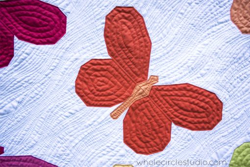 detail of Butterfly Bunch throw size quilt. Designed and made by Sheri Cifaldi-Morrill of Whole Circle Studio with cotton quilting solids. These butterfly patchwork blocks are foundation paper pieced and can be made into the perfect wall hanging, throw, twin, queen or king quilt to give as a gift. 