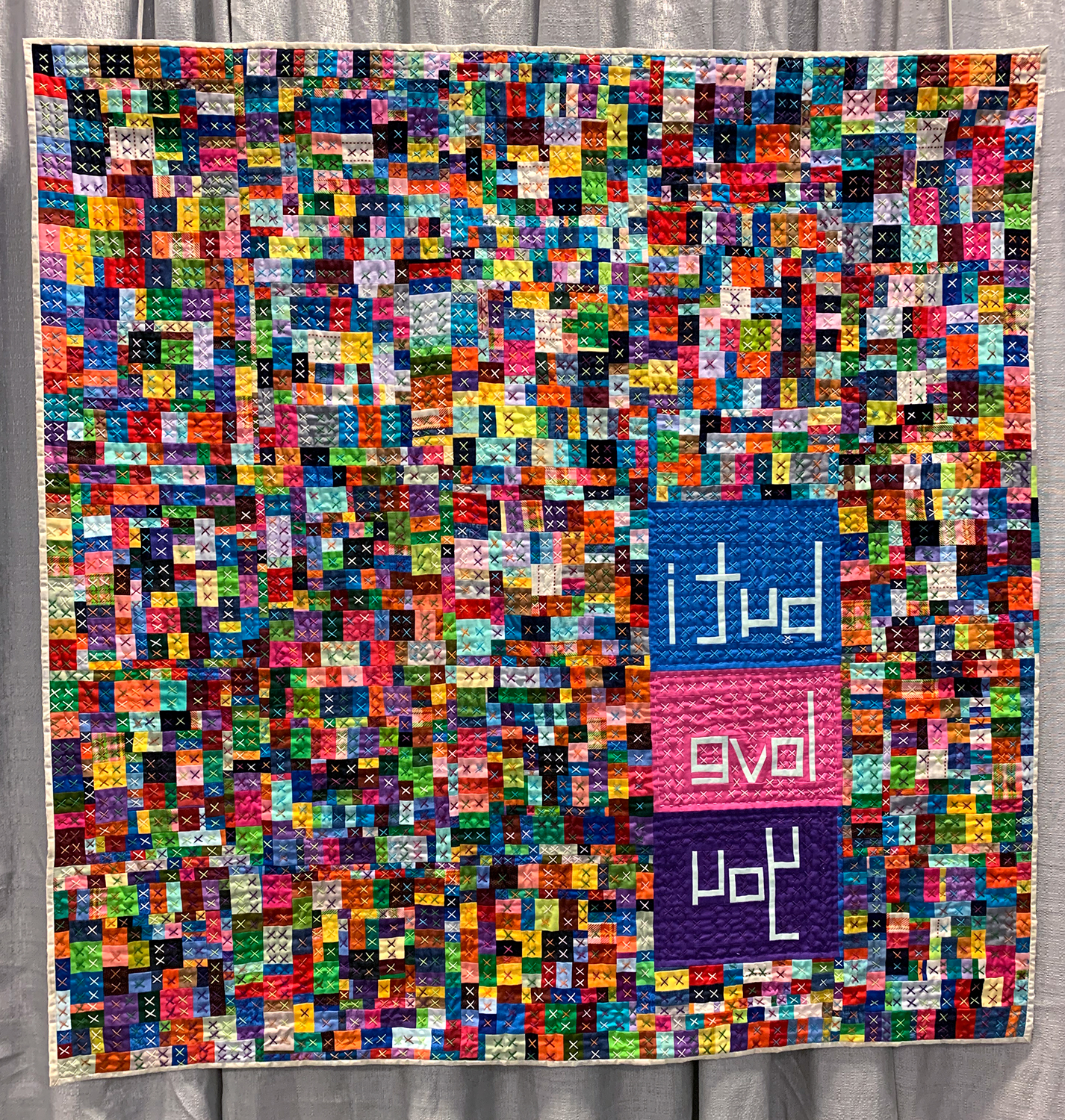 colorful modern quilt with the words "uoy evol i tub" in the lower right corner