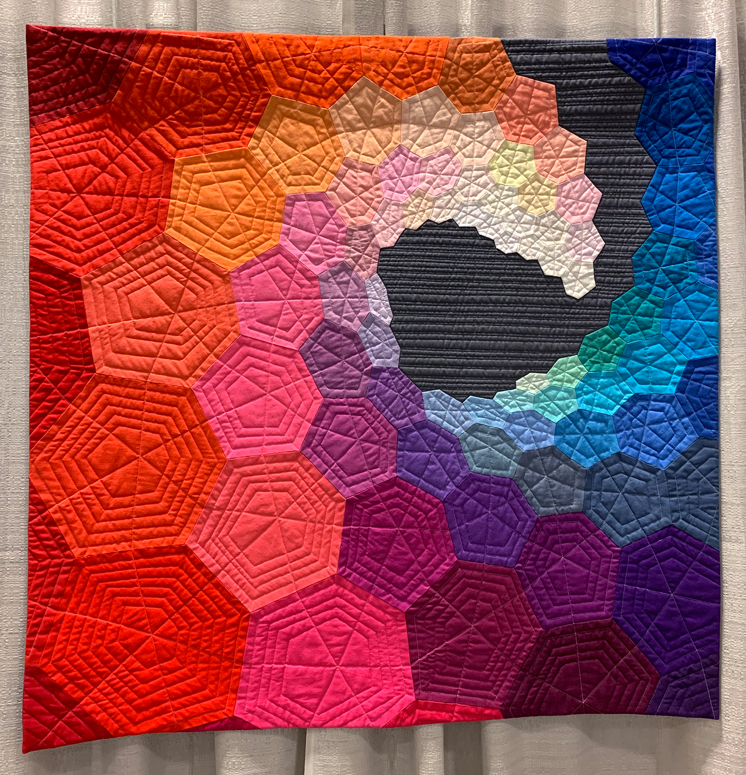 colorful modern quilt showing hexagons in various sizes in a spiral towards the center