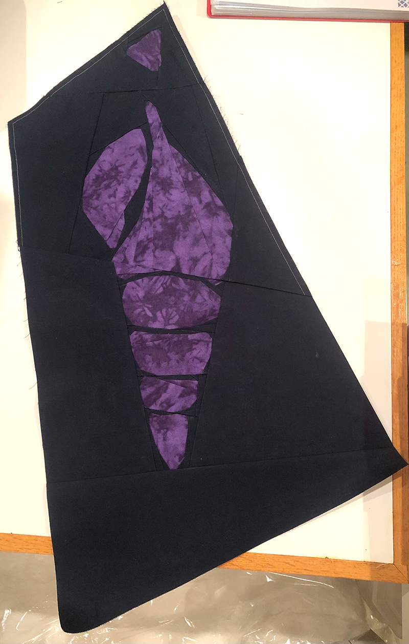 quilt block of an abstract Tulip Shell. Dark purple shell on a black background