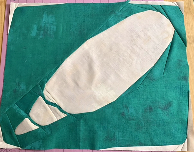 quilt block of an abstract Olive Shell. White shell on aqua background