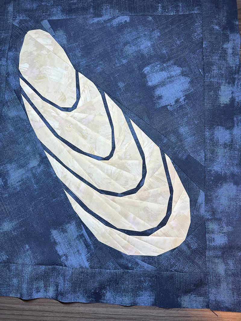 quilt block of an abstract Mussel Shell. White shell on blue background