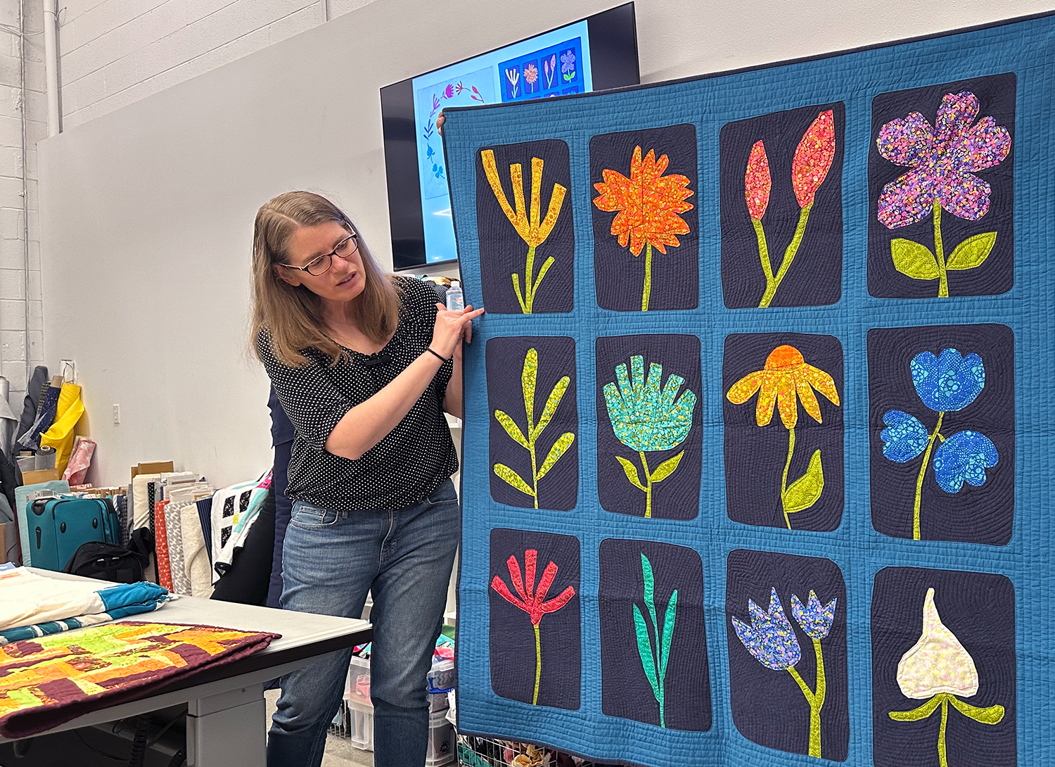 woman giving a presentation and pointing at a quilt