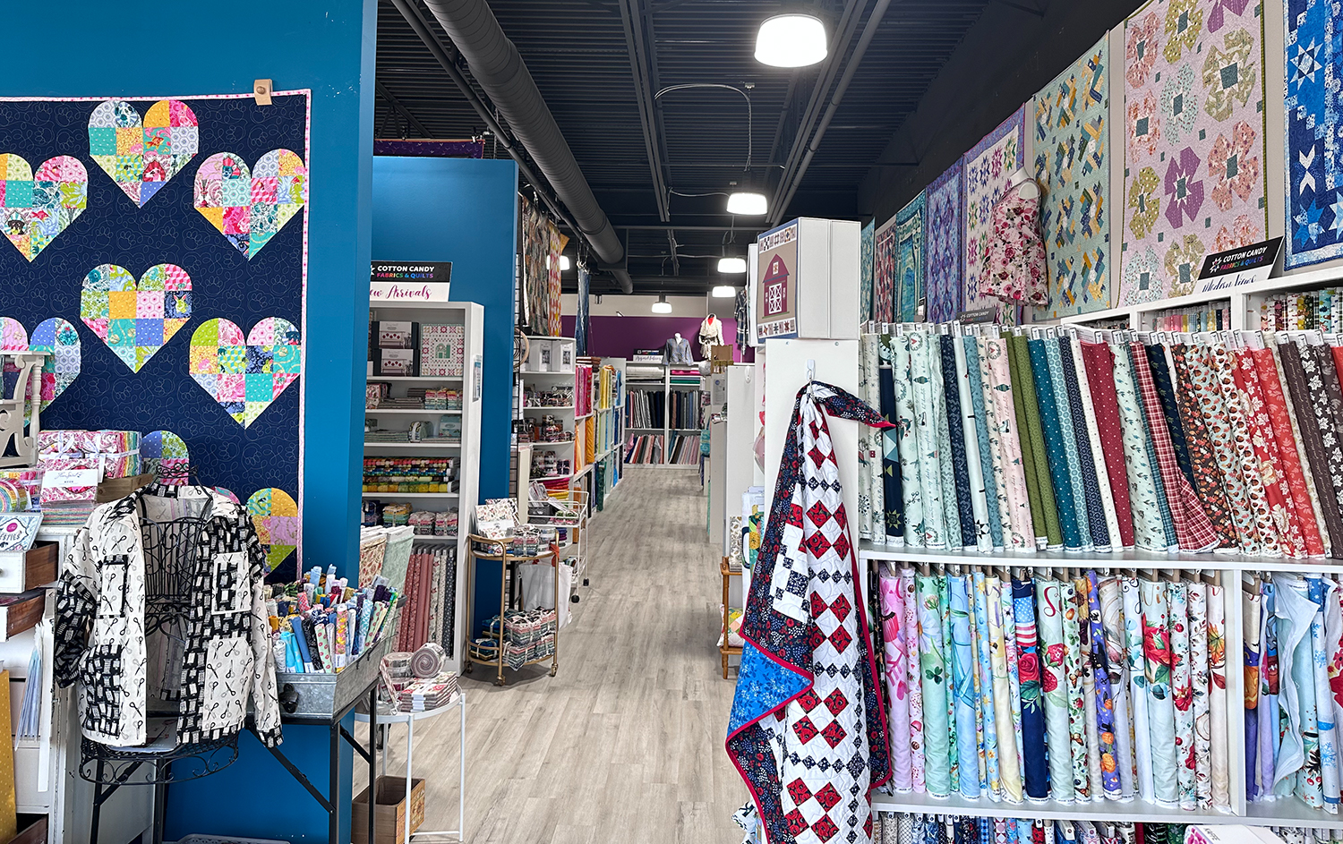 looking down an aisle of a quilt shop with lots of fabric and quilts