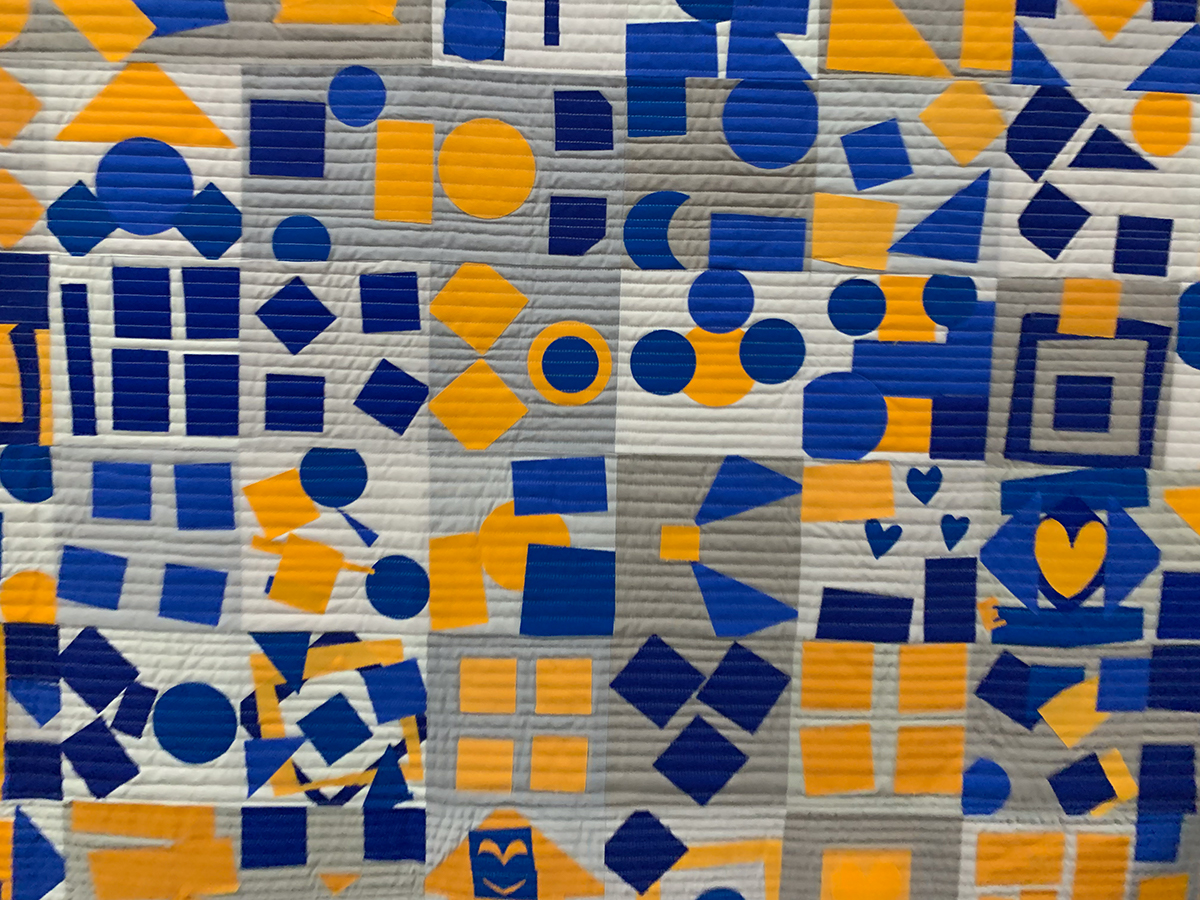 detail of geometric, blue, yellow, and neutral modern quilt
