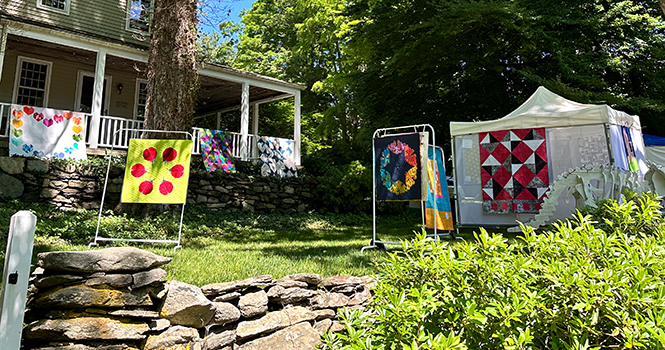 mini quilts hanging in front of a historical home