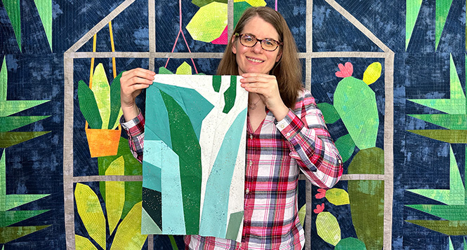 a woman holding a quilt block that looks like leaves