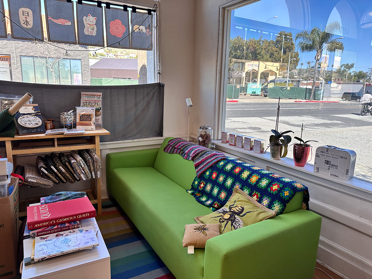 green couch and reading area next to a window inside q quilt shop