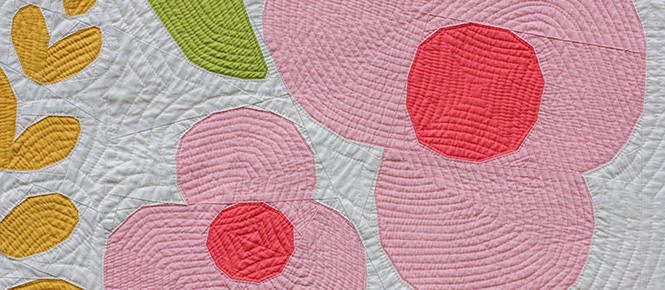 close-up of quilt with large pink and yellow flowers on a white background
