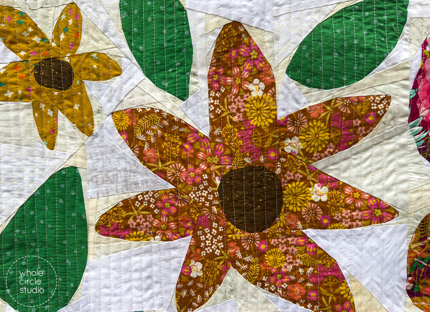 Modern scrappy Wildflower Remix quilt block detail with mixed-color flowers, green leaves, and a textured white and neutral scrappy background.