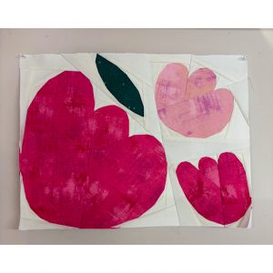 flower quilt block made with textured fabrics pinned to a wall