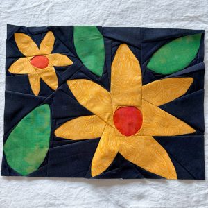 bold yellow paper pieced flower quilt blocks on a dark blue background