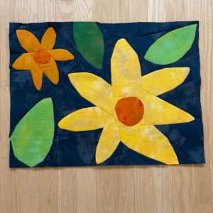 quilt block of large yellow and orange flowers and leaves on a navy background