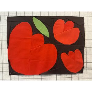 three foundation paper pieced flowers made using red fabric on a navy background