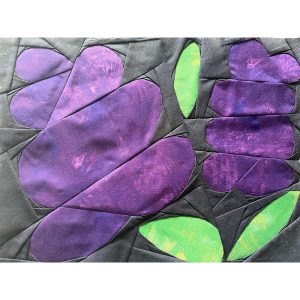 large lilac quilt block made with deep purple, green, and gray fabric