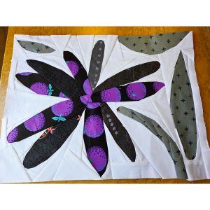 scrappy daisy quilt block made with purple, gray, and white fabric