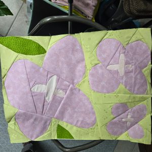 Wildflower quilt block with geometric shapes made with purple and green batik fabric