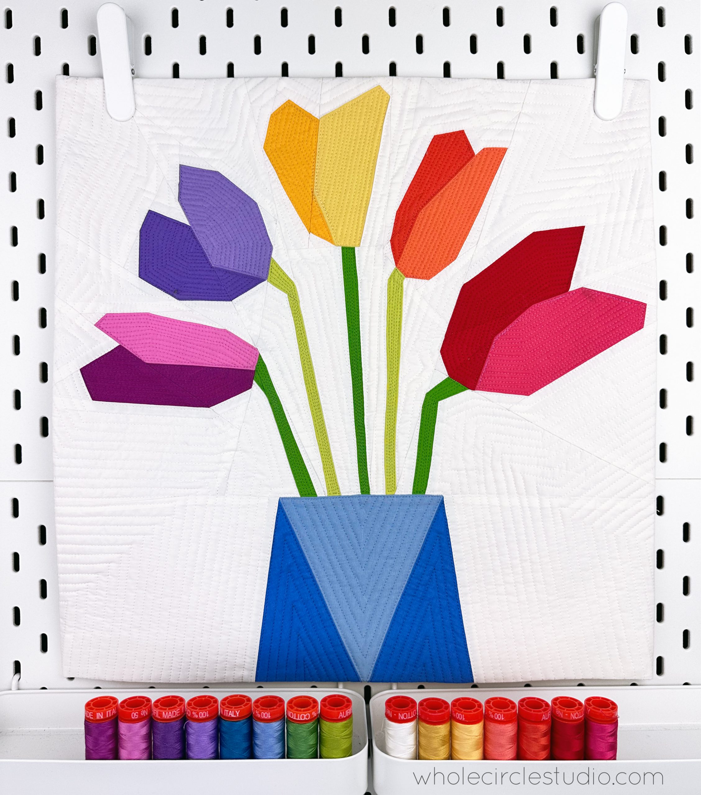 Modern rainbow tulip mini quilt made with foundation paper piecing with 15 colorful thread spools
