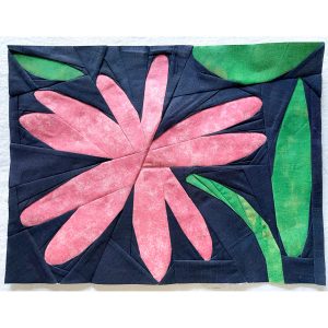 pink daisy quilt block on a light green background