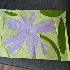light purple daisy quilt block on a light green background