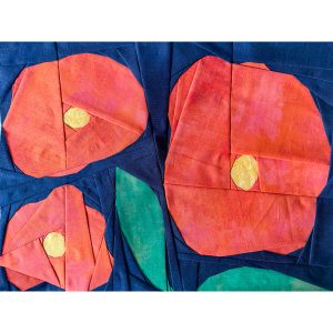 3 abstract orange flowers and 2 green leaves quilt block on a navy background