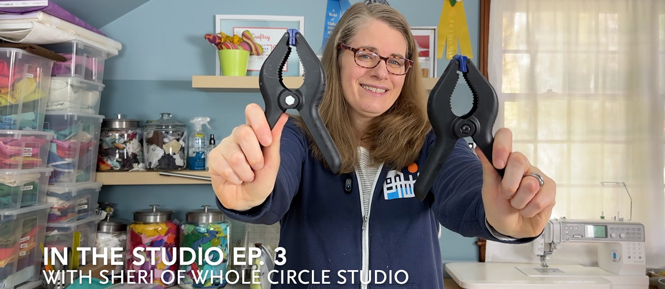 woman holding two black clamps in a sewing space
